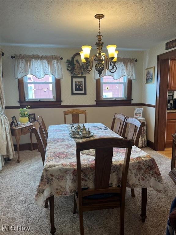 dining room featuring light carpet, a textured ceiling, a chandelier, and a wealth of natural light