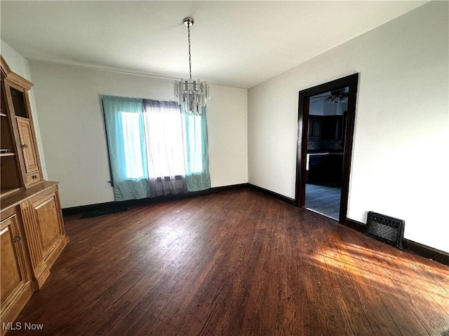 unfurnished room featuring dark wood-style flooring, visible vents, baseboards, and an inviting chandelier