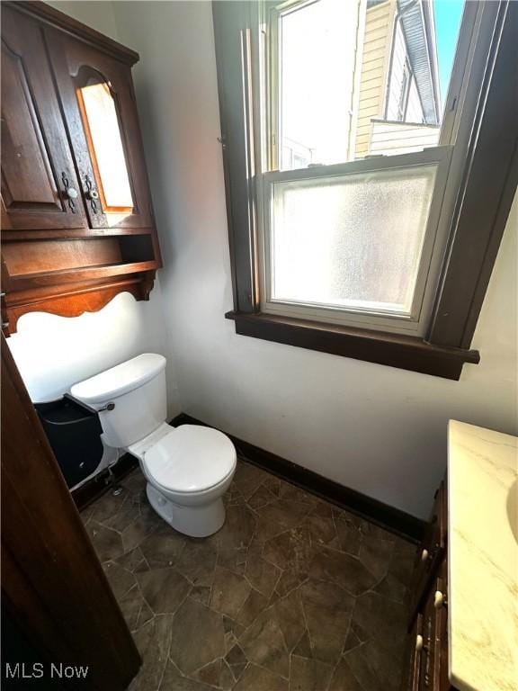 bathroom featuring toilet, vanity, and baseboards