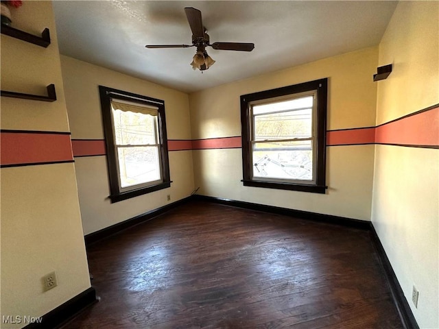 empty room with a ceiling fan, dark wood-style flooring, and baseboards