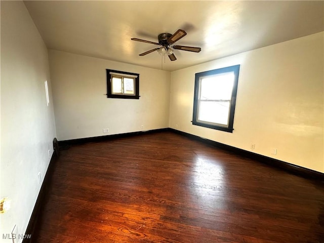 spare room with a healthy amount of sunlight, baseboards, and dark wood finished floors