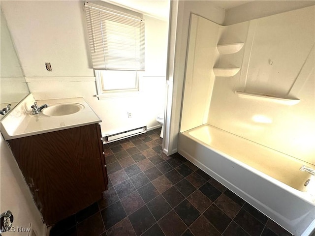 bathroom featuring toilet, vanity, stone finish floor, baseboard heating, and shower / bathtub combination