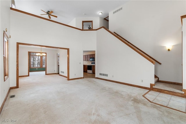 unfurnished living room with stairway, a high ceiling, visible vents, and light colored carpet