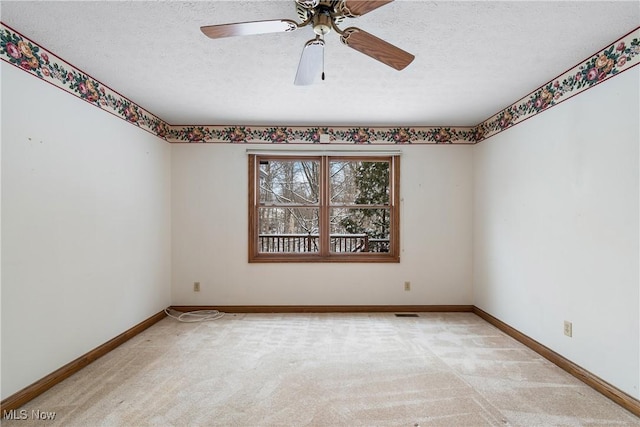 empty room featuring light carpet, a textured ceiling, a ceiling fan, and baseboards