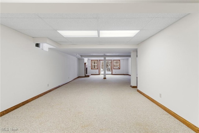 unfurnished room with light carpet, a drop ceiling, and baseboards