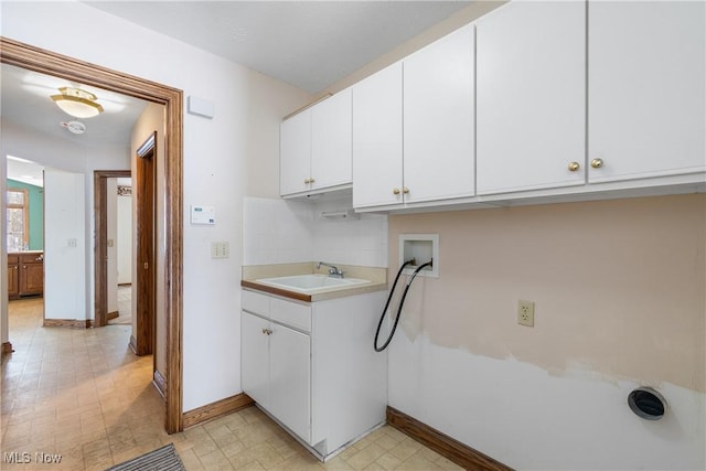 laundry area with cabinet space, baseboards, hookup for a washing machine, light floors, and a sink