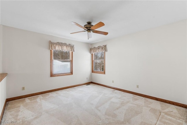 spare room featuring baseboards, a ceiling fan, and light colored carpet