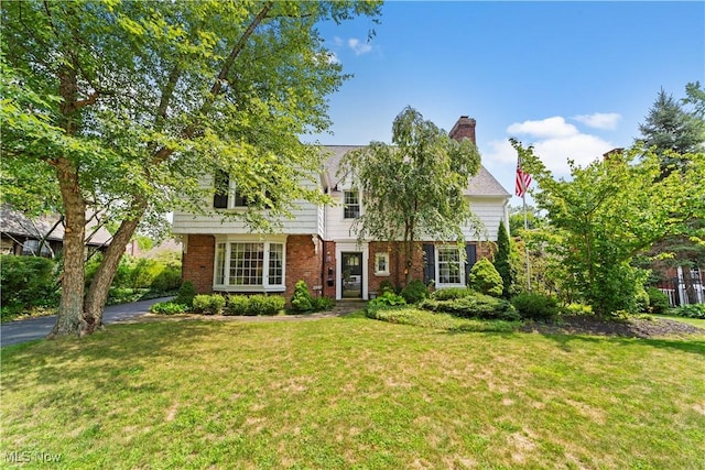 view of front facade featuring a front yard, brick siding, and a chimney