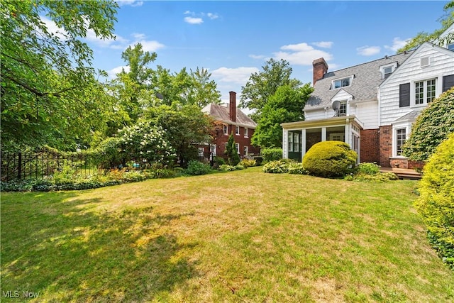 view of yard featuring fence and a sunroom