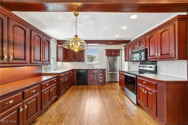 kitchen featuring black appliances, hanging light fixtures, light countertops, and light wood-style floors