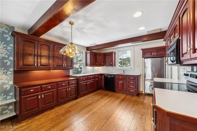 kitchen with decorative light fixtures, stainless steel appliances, light countertops, plenty of natural light, and wallpapered walls