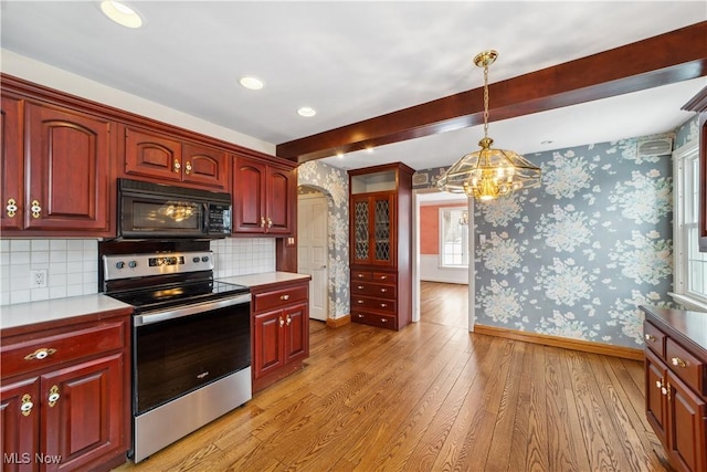 kitchen featuring stainless steel range with electric stovetop, black microwave, light countertops, and wallpapered walls