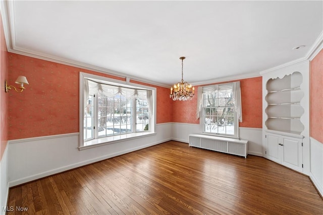 unfurnished dining area featuring radiator heating unit, wainscoting, and a healthy amount of sunlight