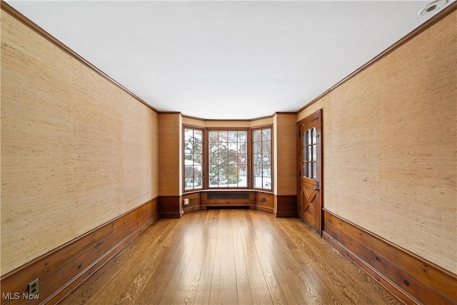 spare room with ornamental molding and wood finished floors