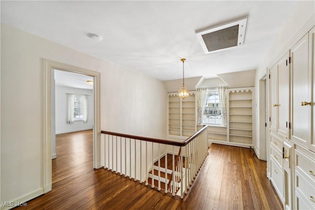 corridor featuring dark wood-style floors, visible vents, an upstairs landing, and baseboards