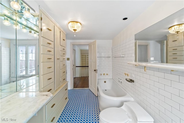 full bath with toilet, a garden tub, and tile walls