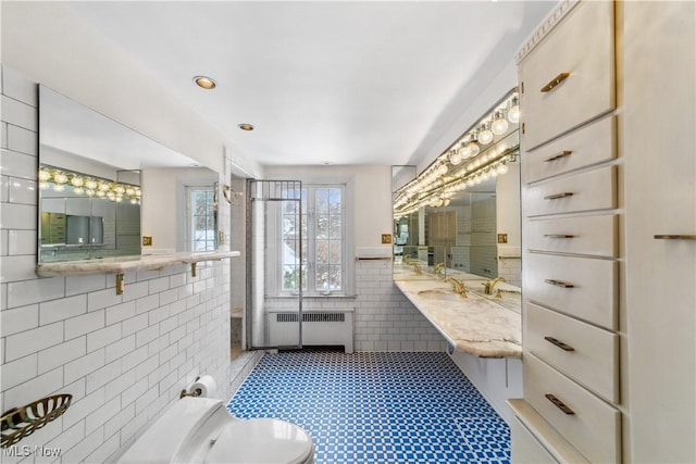 bathroom with toilet, a wainscoted wall, a sink, tile walls, and radiator heating unit