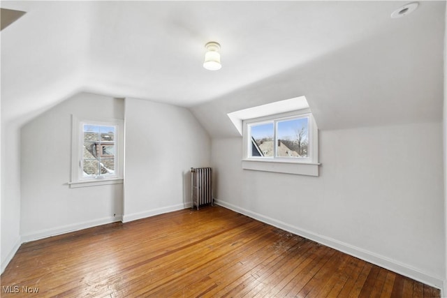 bonus room with baseboards, a healthy amount of sunlight, radiator heating unit, and wood finished floors