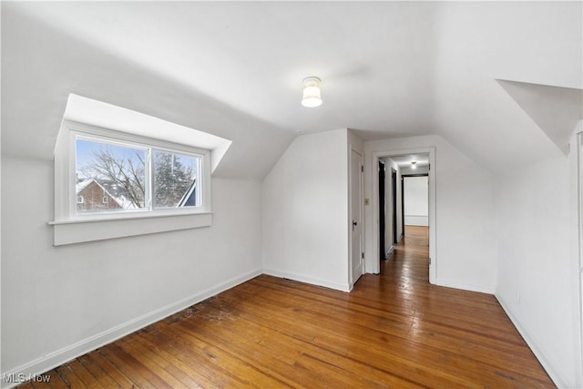 bonus room featuring lofted ceiling, dark wood-style flooring, and baseboards