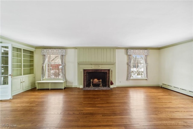 unfurnished living room featuring ornamental molding, a wealth of natural light, a baseboard radiator, and wood finished floors