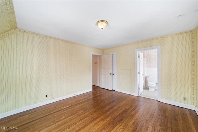 interior space featuring baseboards, wood finished floors, and wallpapered walls