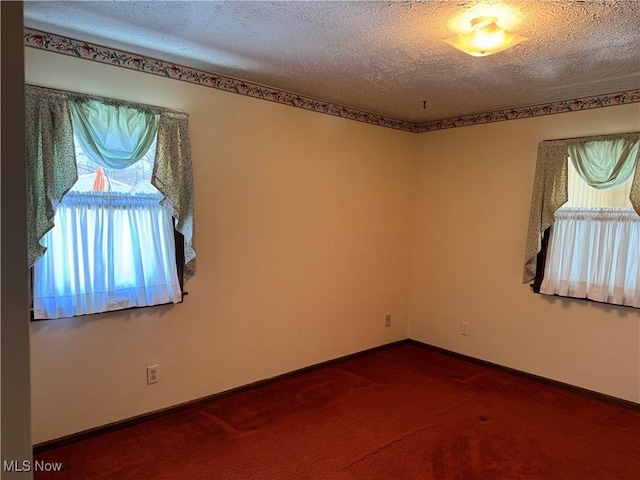 carpeted spare room featuring baseboards and a textured ceiling