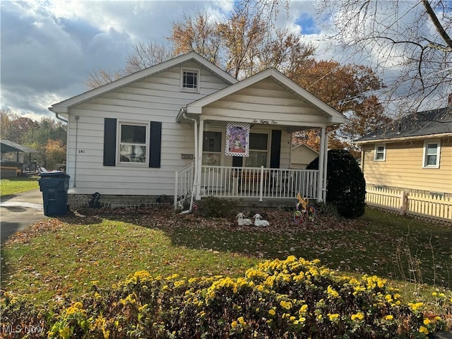 bungalow-style house with covered porch, a front lawn, and fence