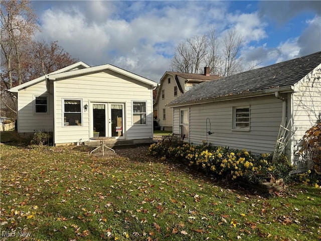 back of house with a yard, french doors, and a shingled roof