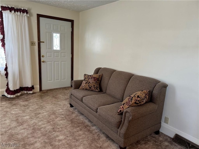 carpeted living room with baseboards, visible vents, and a textured ceiling