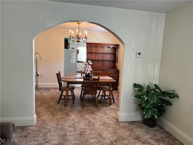 dining area with arched walkways, carpet floors, a textured ceiling, and baseboards