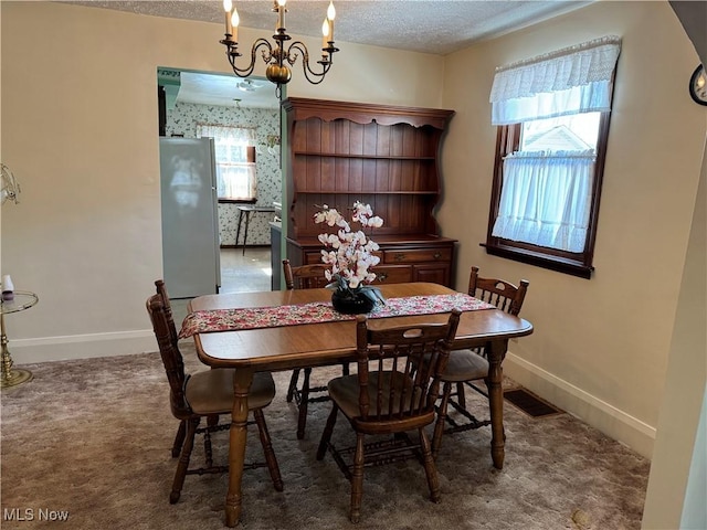 carpeted dining room with visible vents, a textured ceiling, and baseboards