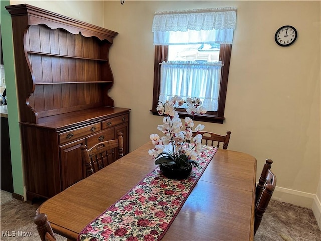 dining area featuring dark colored carpet and baseboards