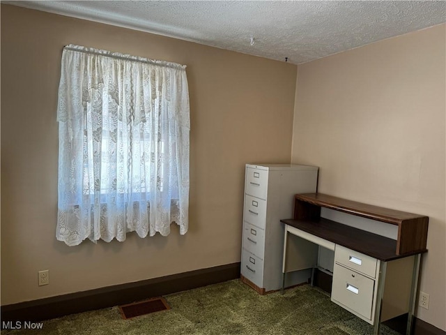 unfurnished office featuring baseboards, visible vents, dark carpet, and a textured ceiling