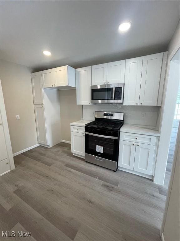 kitchen featuring stainless steel appliances, white cabinets, and light countertops