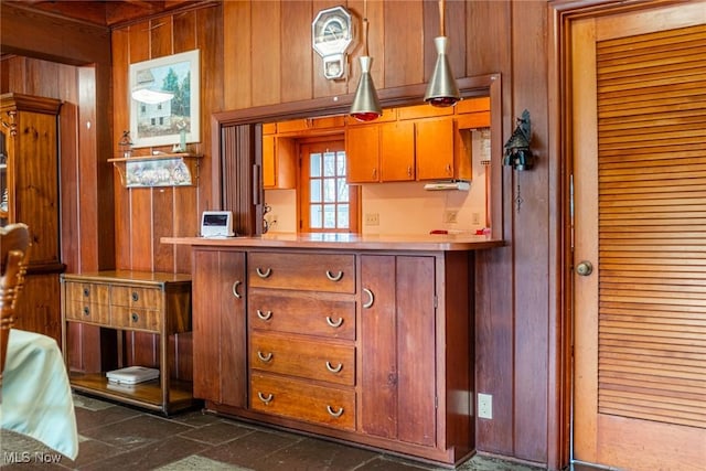 kitchen with light countertops, brown cabinets, and wooden walls