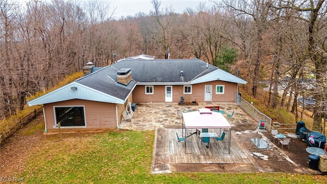 back of property featuring a deck, a forest view, a yard, and outdoor dining area