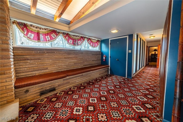 corridor with lofted ceiling with beams and carpet flooring