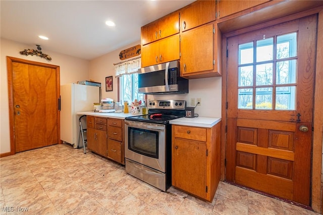 kitchen featuring light countertops, appliances with stainless steel finishes, brown cabinetry, and recessed lighting