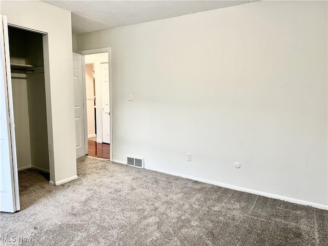 unfurnished bedroom featuring baseboards, visible vents, a textured ceiling, carpet flooring, and a closet