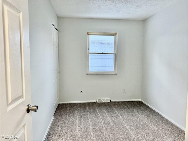 carpeted empty room with a textured ceiling, visible vents, and baseboards