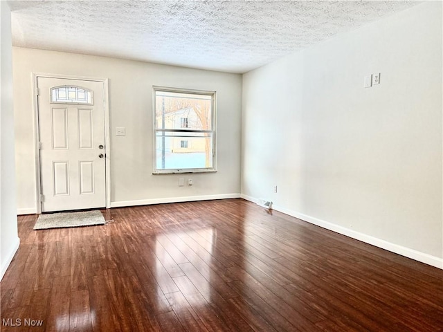 foyer entrance with a textured ceiling, dark wood-type flooring, and baseboards