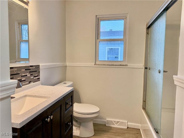 bathroom with visible vents, decorative backsplash, toilet, combined bath / shower with glass door, and vanity