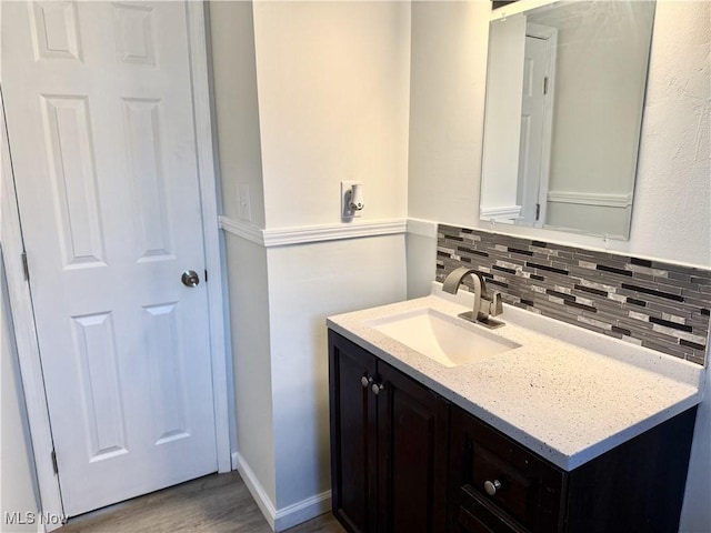 bathroom featuring wood finished floors, vanity, and decorative backsplash