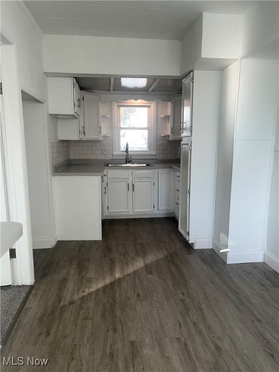 kitchen with dark wood-style floors, dark countertops, a sink, and white cabinets