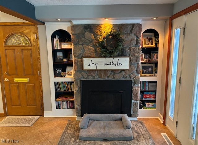 interior space with baseboards, a fireplace, visible vents, and built in features