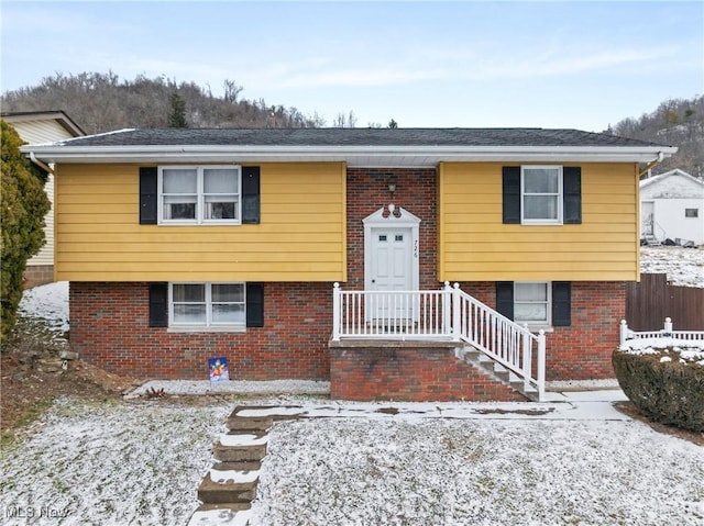 bi-level home featuring brick siding and fence