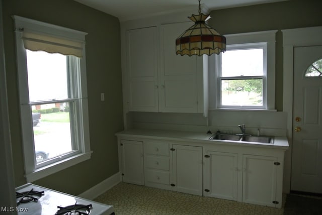 kitchen with white cabinetry, light countertops, a sink, and decorative light fixtures