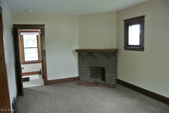 unfurnished living room with a wealth of natural light, visible vents, a fireplace, and carpet