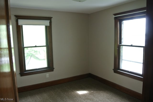 unfurnished room featuring carpet floors, a wealth of natural light, and baseboards