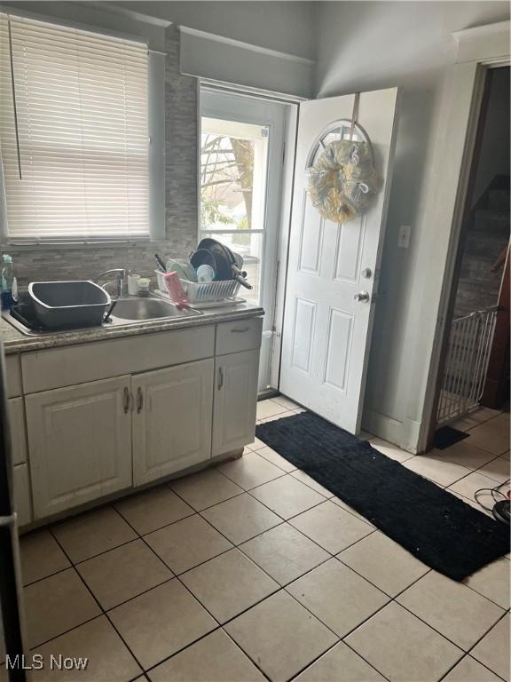 interior space featuring light tile patterned floors, white cabinets, and a sink